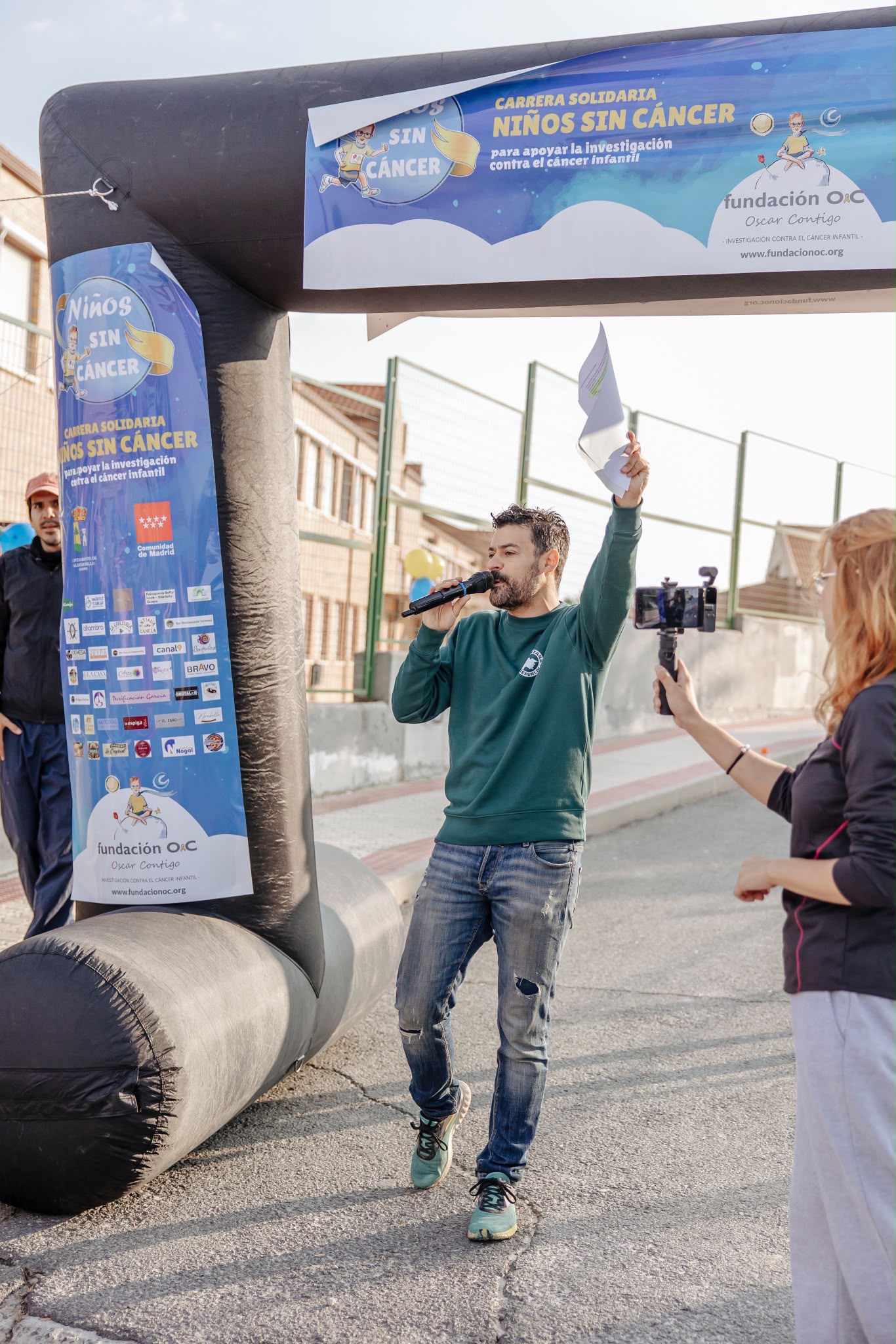 Javier Cáceres animando evento con micrófono bajo arco inflable